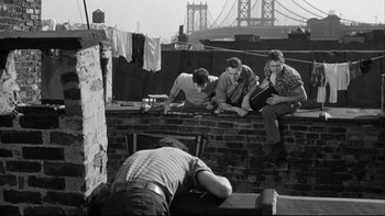 Movie still from “Somebody Up There Likes Me” (1956), directed by Robert Wise – A group of men sitting on top of a brick wall; Wide shot, High angle