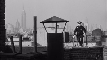 Movie still from “Somebody Up There Likes Me” (1956), directed by Robert Wise – A man in a police uniform standing on top of a building; Wide shot, Low angle