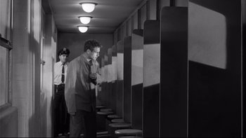 Movie still from “Somebody Up There Likes Me” (1956), directed by Robert Wise – A man in a suit and tie standing in front of a man in a suit and tie; Wide shot, Low angle