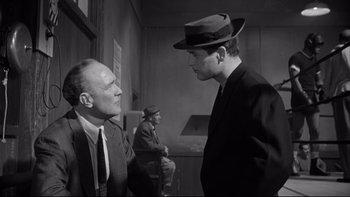 Movie still from “Somebody Up There Likes Me” (1956), directed by Robert Wise – A man in a suit and a hat talking to another man in a suit and a hat; Medium shot, Low angle