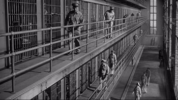 Movie still from “Somebody Up There Likes Me” (1956), directed by Robert Wise – A black and white photo of men in uniform in a jail cell; Extreme Wide shot, High angle