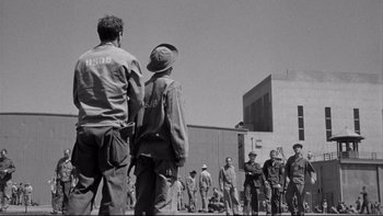 Movie still from “Somebody Up There Likes Me” (1956), directed by Robert Wise – Black and white photograph of men standing in front of a building; Wide shot, Low angle