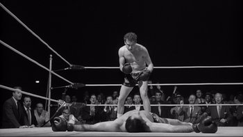 Movie still from “Somebody Up There Likes Me” (1956), directed by Robert Wise – A man standing over another man on a boxing ring; Wide shot, Low angle
