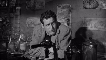 Movie still from “Somebody Up There Likes Me” (1956), directed by Robert Wise – A black and white photo of a man sitting at a table; Close Up shot, Over the shoulder angle