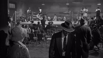 Movie still from “Somebody Up There Likes Me” (1956), directed by Robert Wise – A group of people in a boxing ring with chairs; Wide shot, High angle
