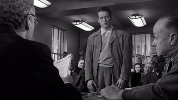 Movie still from “Somebody Up There Likes Me” (1956), directed by Robert Wise – A black and white photo of a man standing in front of a group of people; Medium shot, Low angle