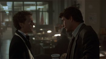 Movie still from “Someone to Watch Over Me” (1987), directed by Ridley Scott – Two men in suits are having a conversation; Medium shot, Over the shoulder angle