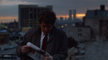 Movie still from “Someone to Watch Over Me” (1987), directed by Ridley Scott – A man in a suit and tie reading a newspaper; Close Up shot, Low angle