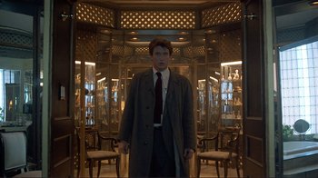 Movie still from “Someone to Watch Over Me” (1987), directed by Ridley Scott – A man in a suit and tie standing in a room; Medium shot, Low angle