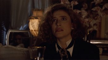 Movie still from “Someone to Watch Over Me” (1987), directed by Ridley Scott – A woman sitting at a table with a glass of wine; Close Up shot, Over the shoulder angle