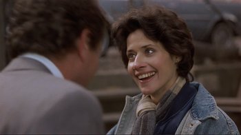 Movie still from “Someone to Watch Over Me” (1987), directed by Ridley Scott – A woman smiling at a man in a jacket; Close Up shot, Over the shoulder angle