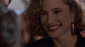Movie still from “Someone to Watch Over Me” (1987), directed by Ridley Scott – A person with curly hair smiling; Close Up shot, Over the shoulder angle