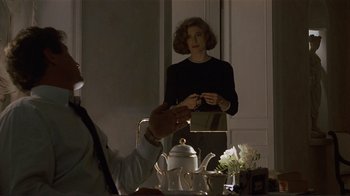 Movie still from “Someone to Watch Over Me” (1987), directed by Ridley Scott – A woman standing in front of a table with a tea pot; Medium shot, Over the shoulder angle