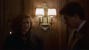 Movie still from “Someone to Watch Over Me” (1987), directed by Ridley Scott – A woman and a man standing in front of a wall light; Medium shot, Over the shoulder angle
