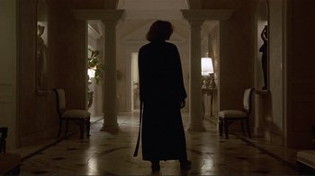 Movie still from “Someone to Watch Over Me” (1987), directed by Ridley Scott – A woman in a long black robe holding a sword; Wide shot, Low angle