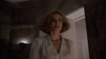 Movie still from “Someone to Watch Over Me” (1987), directed by Ridley Scott – A woman in a white shirt is standing in front of a mirror; Close Up shot, Low angle