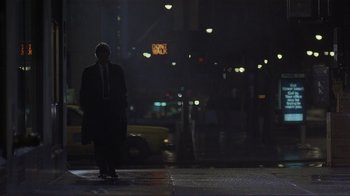 Movie still from “Someone to Watch Over Me” (1987), directed by Ridley Scott – A man is standing on the sidewalk at night; Wide shot, Low angle