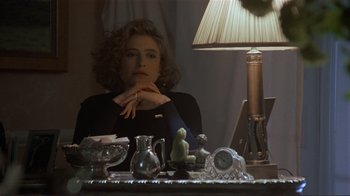 Movie still from “Someone to Watch Over Me” (1987), directed by Ridley Scott – A woman sitting in front of a table with a lamp; Close Up shot, Over the shoulder angle