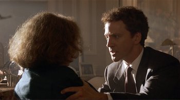 Movie still from “Someone to Watch Over Me” (1987), directed by Ridley Scott – A man in a business suit and tie talking to a woman in a business suit; Close Up shot, Over the shoulder angle