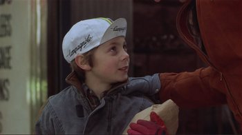 Movie still from “Someone to Watch Over Me” (1987), directed by Ridley Scott – A boy wearing a baseball cap is holding onto a hot dog; Close Up shot, Over the shoulder angle