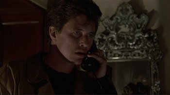 Movie still from “Someone to Watch Over Me” (1987), directed by Ridley Scott – A man talking on a phone in a dark room; Close Up shot, Low angle