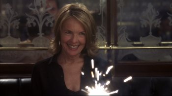 Movie still from “Something's Gotta Give” (2003), directed by Nancy Meyers – A woman smiles while holding a sparkler in her hand; Close Up shot, Over the shoulder angle