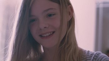 Movie still from “Somewhere” (2010), directed by Sofia Coppola – A young girl smiling for the camera; Close Up shot, Over the shoulder angle
