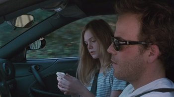 Movie still from “Somewhere” (2010), directed by Sofia Coppola – A man and a woman sitting in a car looking at a cell phone; Close Up shot, Over the shoulder angle