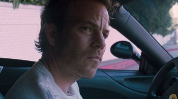 Movie still from “Somewhere” (2010), directed by Sofia Coppola – A person sitting in a car looking at the camera; Close Up shot, Low angle