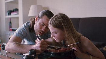 Movie still from “Somewhere” (2010), directed by Sofia Coppola – A man and a young girl working together on a guitar; Medium shot, Low angle