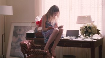Movie still from “Somewhere” (2010), directed by Sofia Coppola – A woman sitting at a desk looking at her cell phone; Medium shot, High angle
