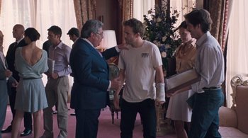Movie still from “Somewhere” (2010), directed by Sofia Coppola – A man in a white shirt is shaking hands with an older man; Medium shot, Over the shoulder angle