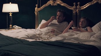 Movie still from “Somewhere” (2010), directed by Sofia Coppola – A man sitting on a bed with a glass of wine; Medium shot, Overhead angle