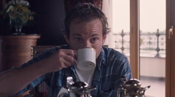 Movie still from “Somewhere” (2010), directed by Sofia Coppola – A man drinking a cup of coffee from a white mug; Close Up shot, Low angle