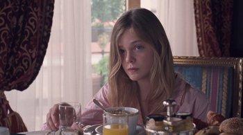 Movie still from “Somewhere” (2010), directed by Sofia Coppola – A girl sitting at a table with a bowl of cereal and a glass; Close Up shot, Over the shoulder angle