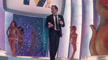 Movie still from “Somewhere” (2010), directed by Sofia Coppola – A man holding a microphone while standing on a stage; Wide shot, Over the shoulder angle