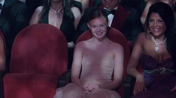 Movie still from “Somewhere” (2010), directed by Sofia Coppola – A girl in a dress sitting in a chair in a theater; Medium shot, High angle