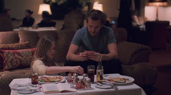 Movie still from “Somewhere” (2010), directed by Sofia Coppola – A man and a woman sitting at a dinner table; Medium shot, Over the shoulder angle