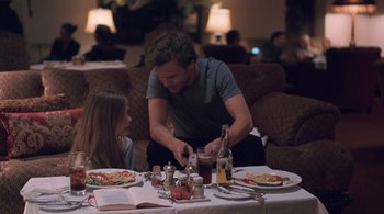Movie still from “Somewhere” (2010), directed by Sofia Coppola – A man and a woman sitting at a table with plates of food; Medium shot, Over the shoulder angle