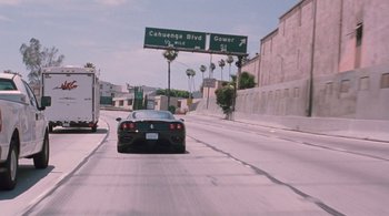 Movie still from “Somewhere” (2010), directed by Sofia Coppola – A black sports car driving down a street; Wide shot, High angle