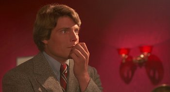 Movie still from “Somewhere in Time” (1980), directed by Jeannot Szwarc – A man in a suit and tie is sitting in front of a red wall; Close Up shot, Over the shoulder angle