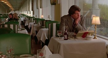 Movie still from “Somewhere in Time” (1980), directed by Jeannot Szwarc – A man sitting at a table in front of a book; Medium shot, Over the shoulder angle