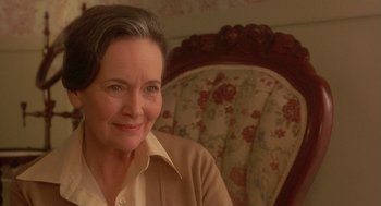 Movie still from “Somewhere in Time” (1980), directed by Jeannot Szwarc – An older woman sitting in a chair smiling for the camera; Close Up shot, Over the shoulder angle