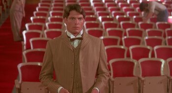 Movie still from “Somewhere in Time” (1980), directed by Jeannot Szwarc – A man standing in front of rows of red chairs; Medium shot, Over the shoulder angle