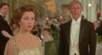 Movie still from “Somewhere in Time” (1980), directed by Jeannot Szwarc – A man and a woman in formal wear standing in front of a crowd of onlookers; Close Up shot, Over the shoulder angle