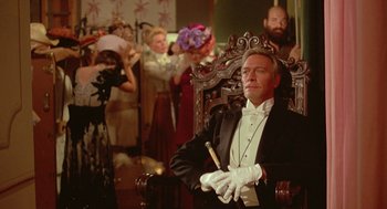 Movie still from “Somewhere in Time” (1980), directed by Jeannot Szwarc – A man in a tuxedo sitting in a chair; Medium shot, Low angle