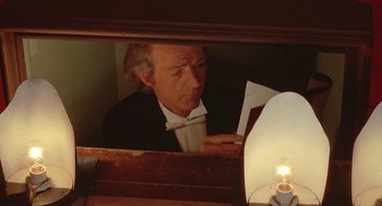 Movie still from “Somewhere in Time” (1980), directed by Jeannot Szwarc – A man in a tuxedo looking at a piece of paper in front of a mirror; Close Up shot, Low angle