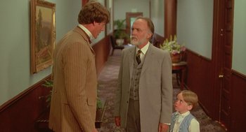 Movie still from “Somewhere in Time” (1980), directed by Jeannot Szwarc – Two men and a little girl standing in a hallway; Medium shot, Over the shoulder angle