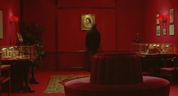 Movie still from “Somewhere in Time” (1980), directed by Jeannot Szwarc – A man standing in front of a painting in a red room; Wide shot, High angle