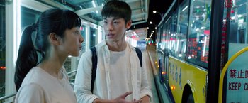 Two young people are talking on a train platform